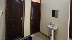 A hallway with two wooden doors, a white sink, and a ceiling light. - Lux Suites Ole Nairi Holiday Homes (Ngong)