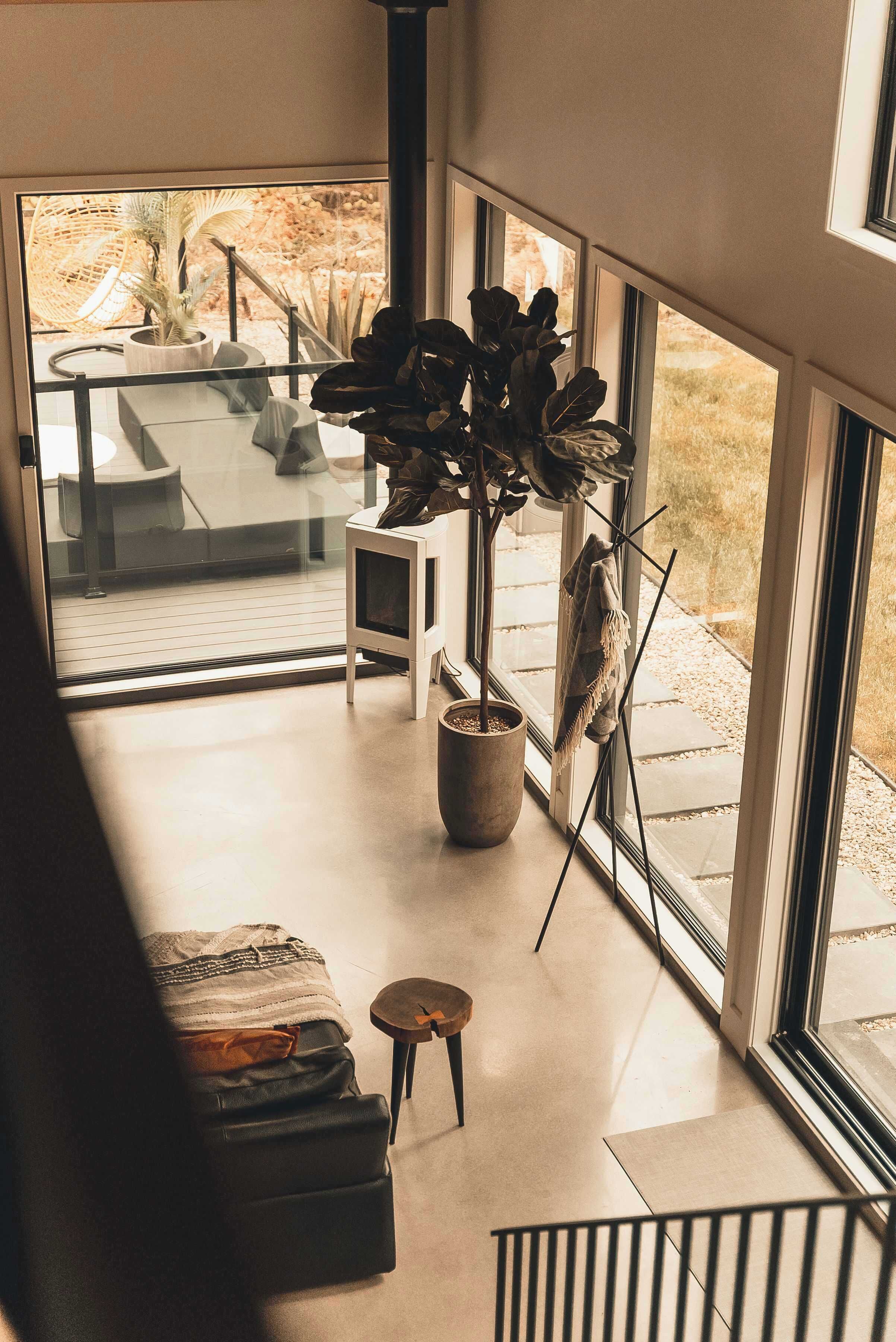 Un salon moderne avec une grande fenêtre, une plante en pot, une petite table et un canapé.