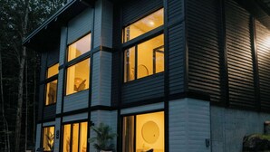 Une maison moderne à deux étages, dotée de grandes fenêtres, d’un panneau solaire et d’une pelouse bien entretenue.
