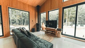 Een moderne woonkamer met een zwarte leren bank, een grote televisie en een houten vloer.