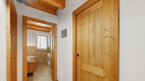 A wooden hallway with a door, a mirror, and a washing machine.