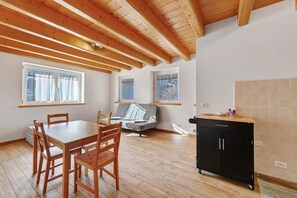A dining area with a wooden table and chairs, a sofa, and a kitchen area with a black cabinet.