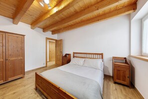A bedroom with a wooden bed, a wooden wardrobe, and a nightstand.