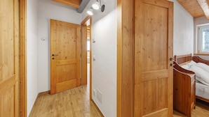 A wooden interior with a hallway leading to a bedroom with a bed.
