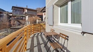 A balcony with wooden railings, a table, and benches.