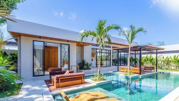 A modern house with a swimming pool, outdoor seating, and lush greenery. - Villa Linaria by Pertama Stay (Ungasan)