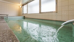 Una piscina con superficie de agua cristalina, barandilla de metal y ventanas con vidrio esmerilado.
