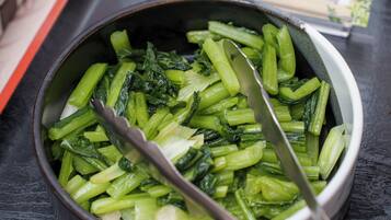 A bowl of cooked green vegetables with a spoon.