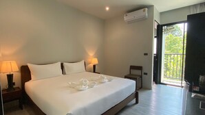 A hotel room with a large bed, two bedside lamps, an air conditioning unit, a chair, and a balcony with a view of greenery. - O2 The Residence (Kanchanaburi)