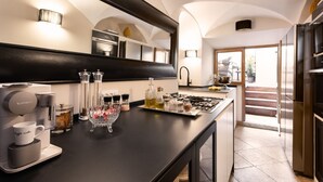 A modern kitchen with a coffee machine, glassware, and a large mirror. - Idyllia | Luxury home with terrace (Rome)