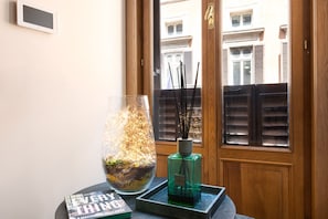 A room with a wooden door, a glass vase with dried plants, a book titled 'EVERYTHING,' and a green bottle. - Idyllia | Luxury home with terrace (Rome)