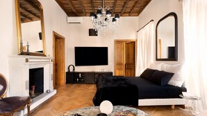 A bedroom with a bed, a TV, a fireplace, and a chandelier. - Idyllia | Luxury home with terrace (Rome)