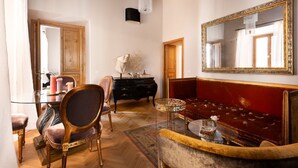 A room with a glass dining table, a red sofa, a large mirror, and a wooden ceiling. - Idyllia | Luxury home with terrace (Rome)