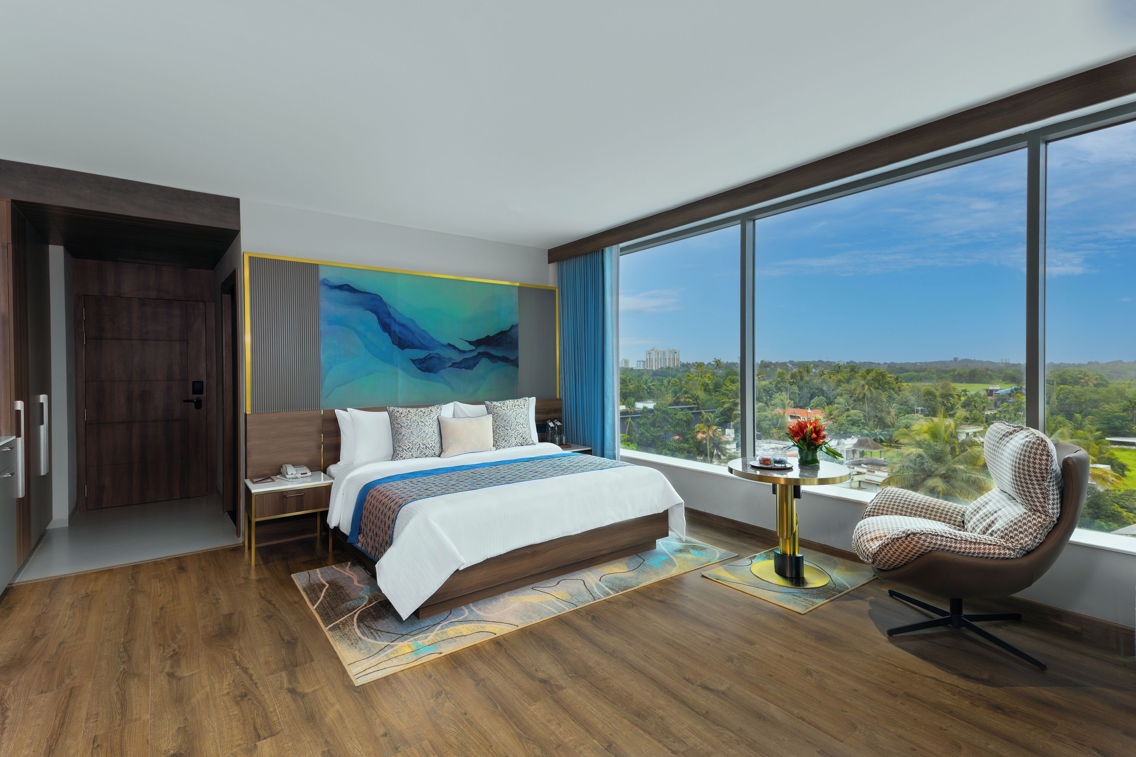 A modern hotel room with a large bed, a view of the city, and a large window.