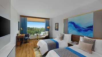 Ein Hotelzimmer mit zwei Betten, einem Schreibtisch, einem Stuhl, einem Fernseher und einem großen Fenster mit Blick.