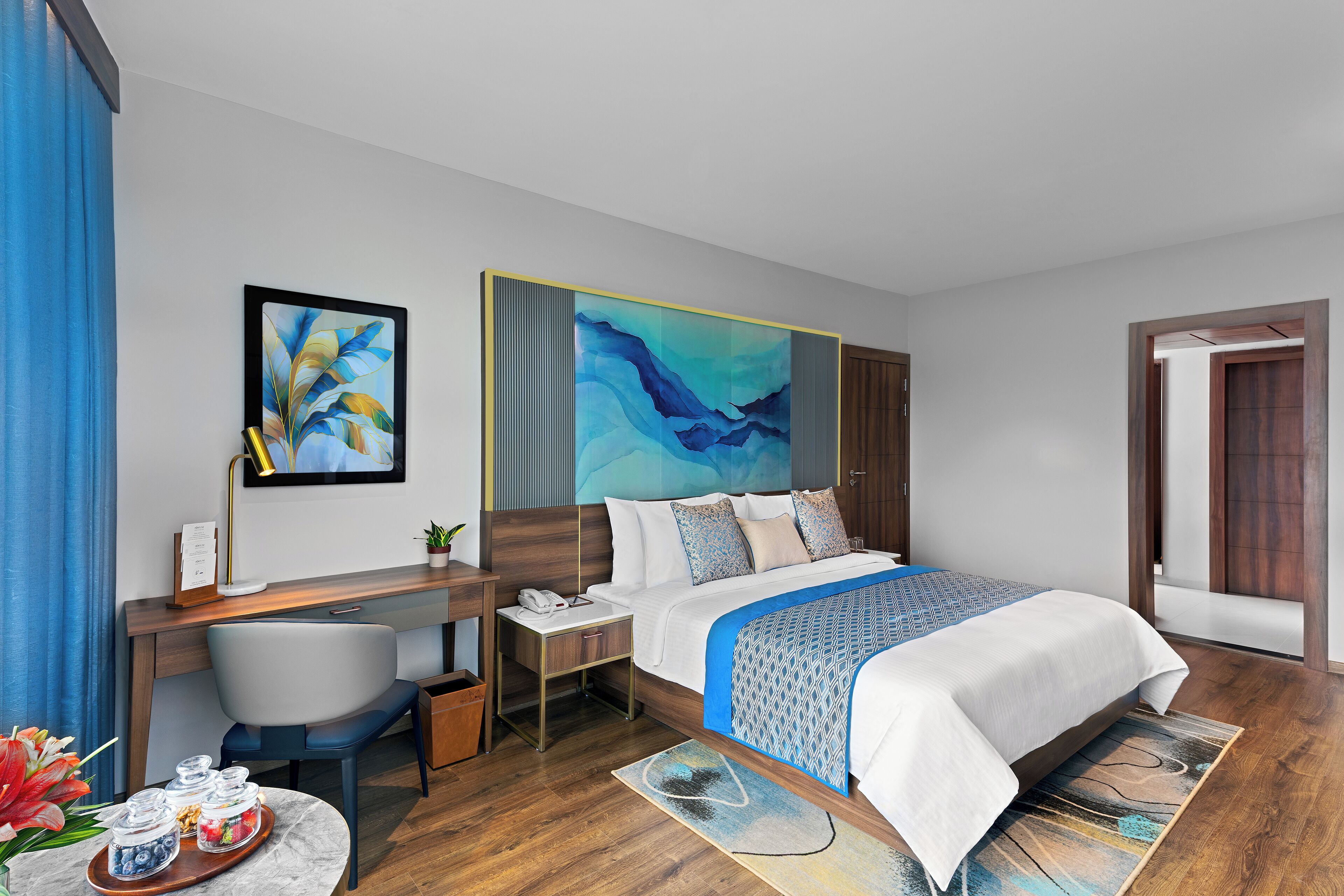 Una habitación de hotel moderna con cama, escritorio, silla y obras de arte.