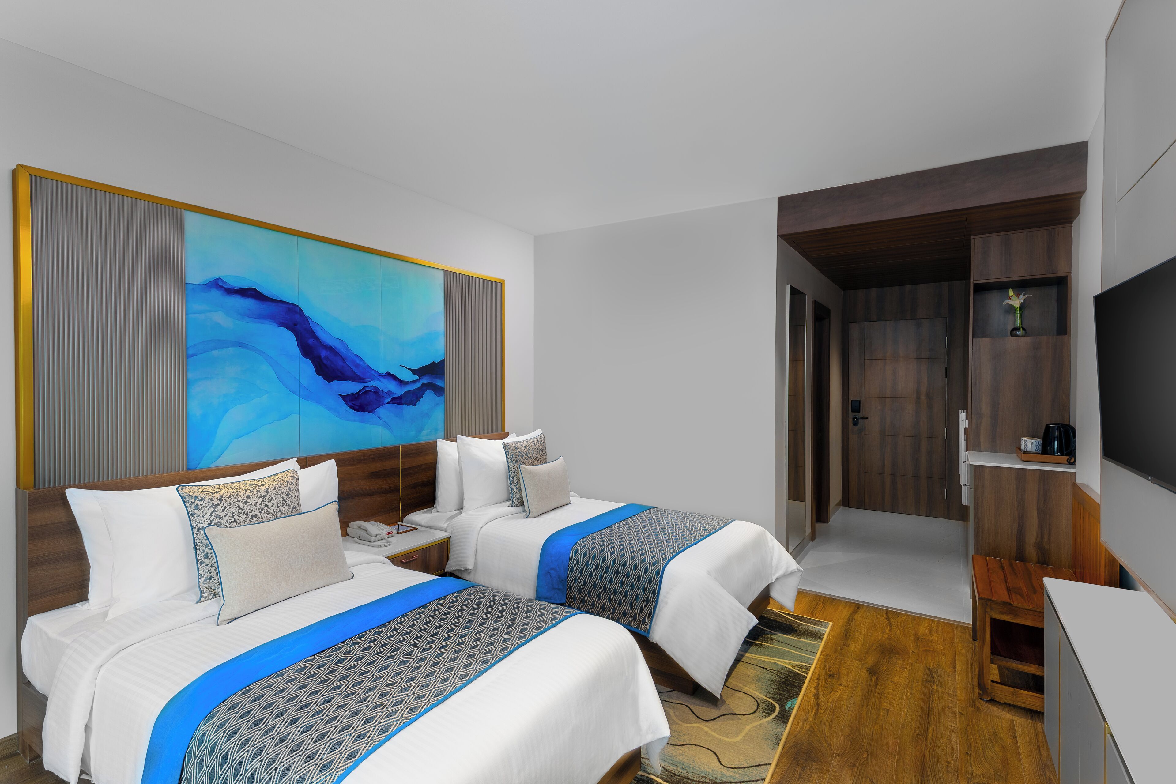 A hotel room with two beds, a large abstract painting, a television, and a wooden cabinet.