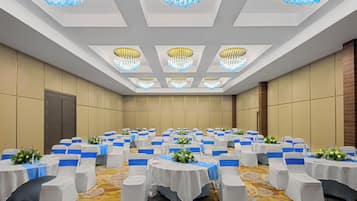 Una sala de conferencias con mesas redondas, sillas blancas y lazos azules.
