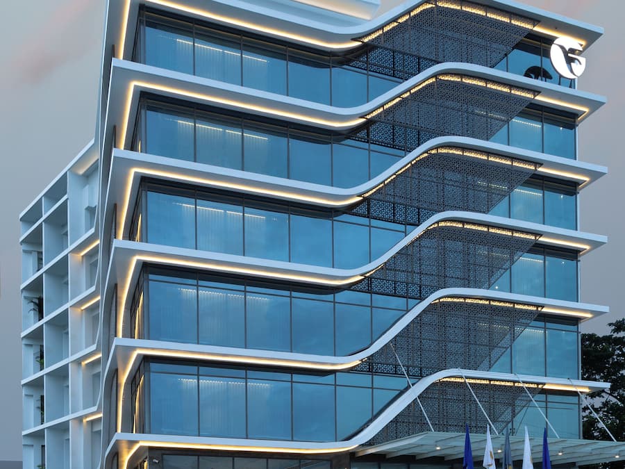 Un hotel moderno con varios pisos, ventanas amplias y una entrada destacada con banderas.