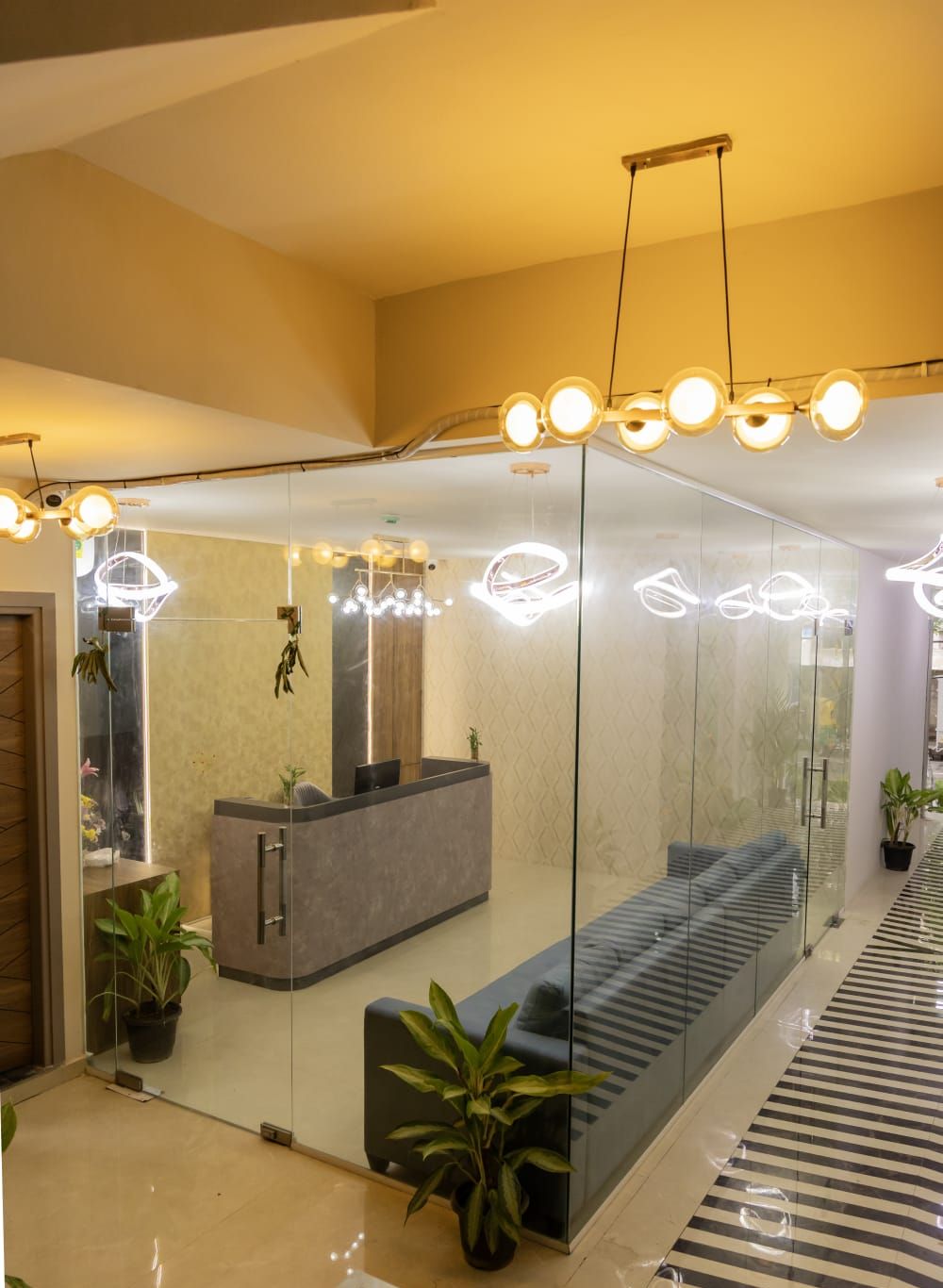 A modern reception area with a glass partition, a reception desk, seating area, and a patterned floor.