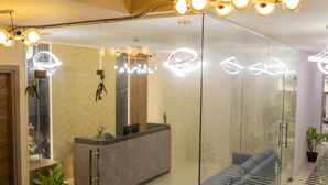 A modern reception area with a glass partition, a reception desk, seating area, and a patterned floor. - Seaesta -- Business Stay (Bengaluru)
