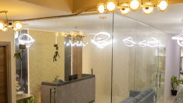 A modern reception area with a glass partition, a reception desk, seating area, and a patterned floor.