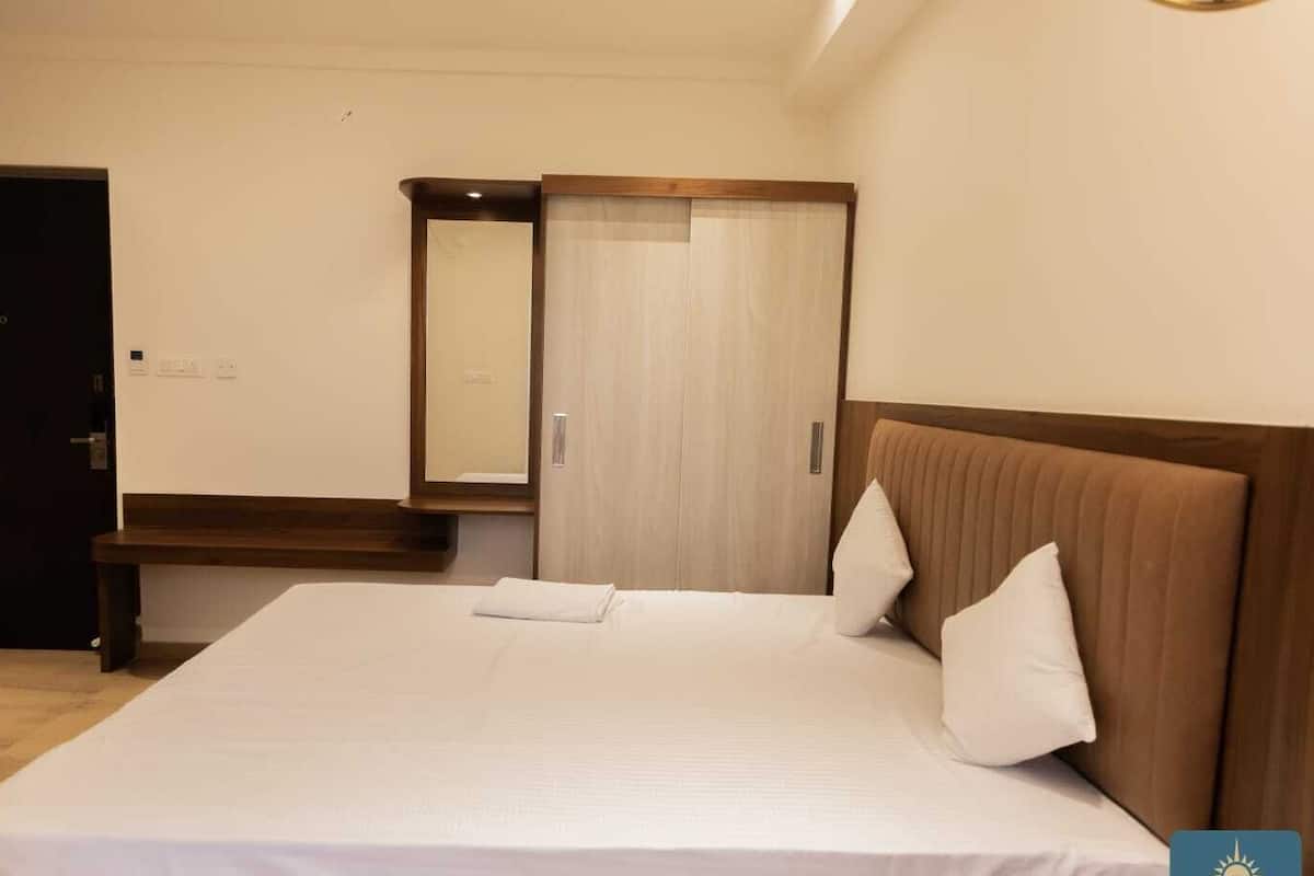 Una habitación de hotel con una cama grande, un cabecero de madera, un espejo y un armario.