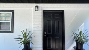 A modern building entrance with a black door, white brick walls, and two potted plants. - 2 Bdrm 2 Ba Gem, Where Comfort Meets Convenience
Sports, Fun, Eats & Campus Life (Arlington)