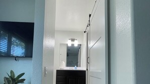A hallway leading to a bathroom with a sink, mirror, and towel rack. - 2 Bdrm 2 Ba Gem, Where Comfort Meets Convenience
Sports, Fun, Eats & Campus Life (Arlington)