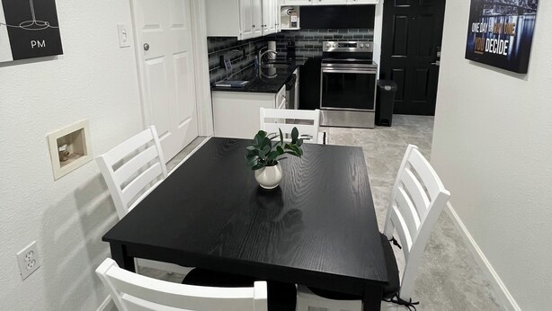 A dining area with a black table, white chairs, and a potted plant. - 2 Bdrm 2 Ba Gem, Where Comfort Meets Convenience
Sports, Fun, Eats & Campus Life (Arlington)