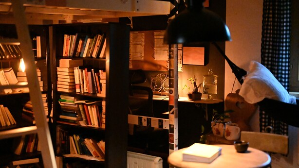 A cozy reading nook with a bookshelf, a small table with a book, a lamp, and a teddy bear. - Peaceful Alpine Hideaway | Between Mountains & Streams (Bad Gastein)