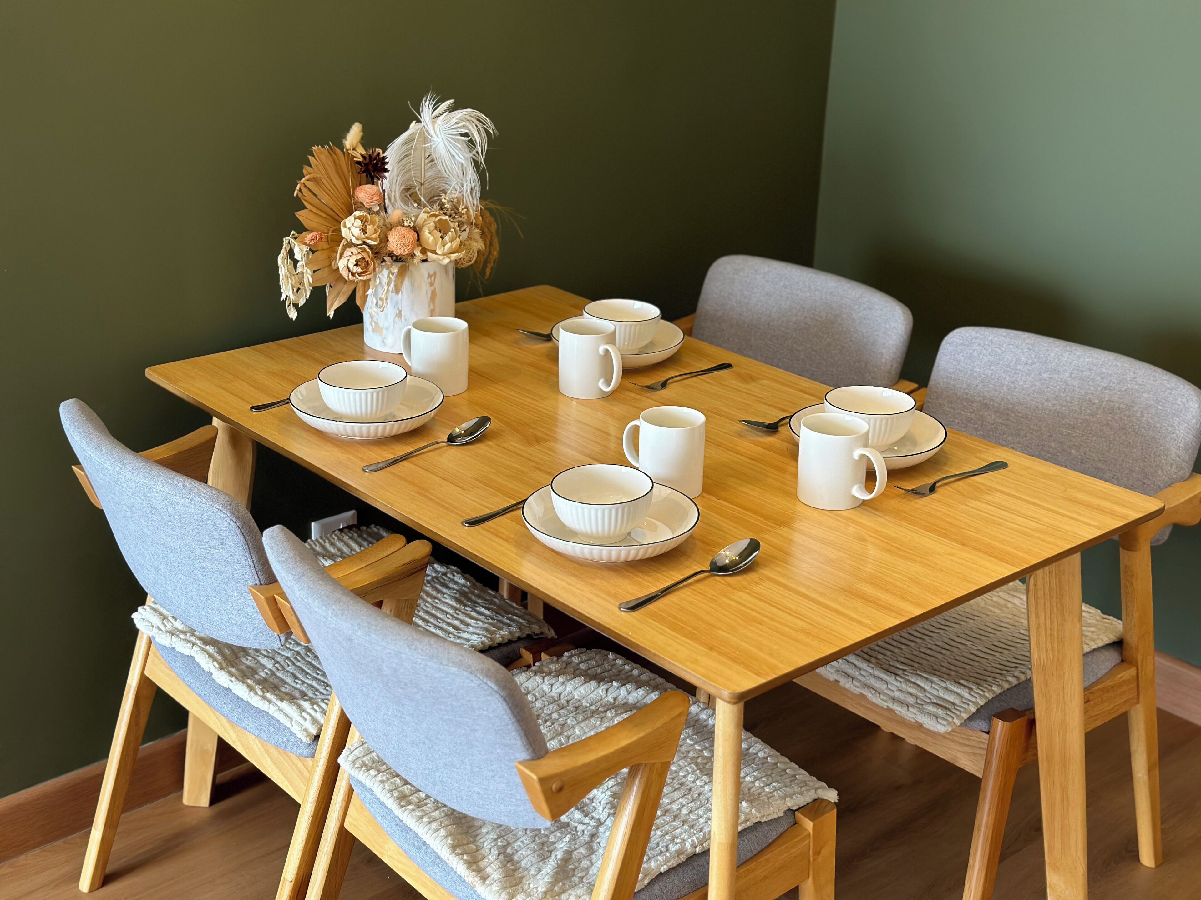 A dining table set with white plates, bowls, and cups, accompanied by silverware.