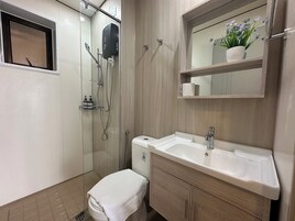 Un baño moderno con ducha de vidrio, lavamanos blanco y tocador de madera.