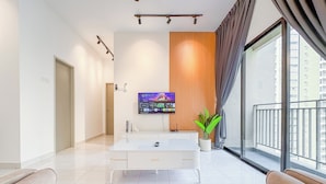 Una sala de estar moderna con un televisor de pantalla plana, un ventanal grande y una planta en maceta.