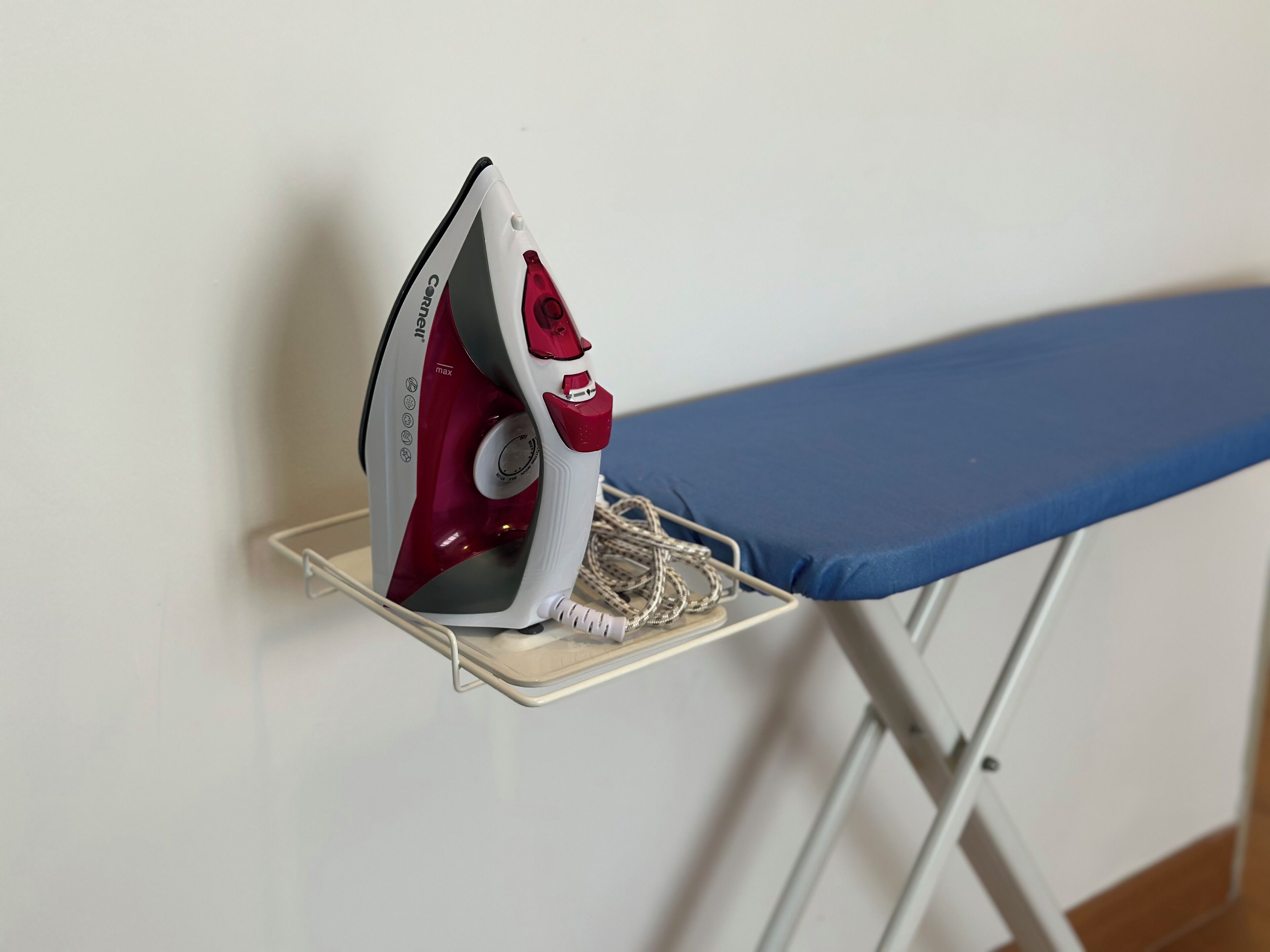 An iron on a stand with a blue ironing board.