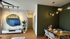 Una sala de estar moderna con televisor, sofá, mesa de comedor y sillas.
