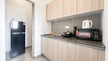 Una cocina moderna con un refrigerador, un horno microondas y una tetera sobre la encimera.