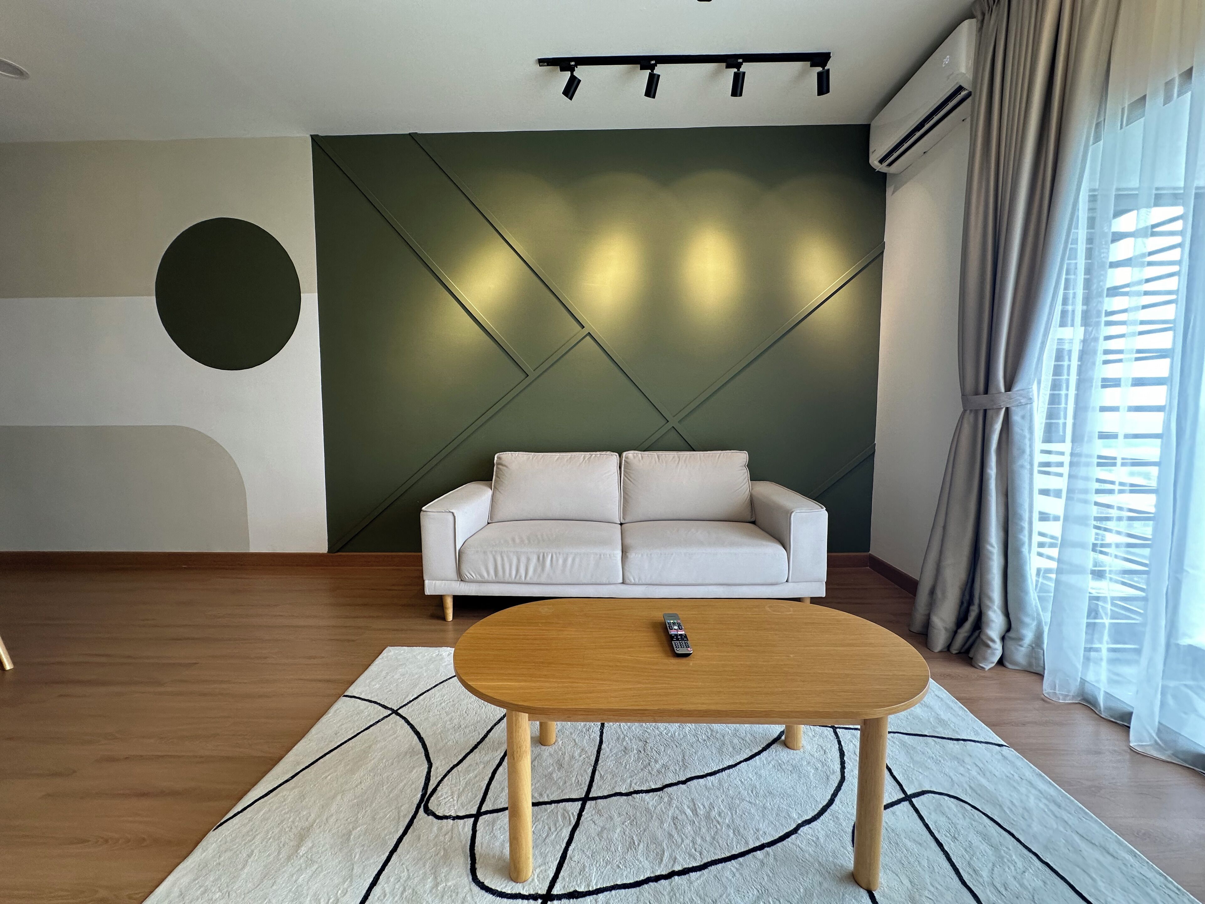 A modern living room with a white sofa, a wooden coffee table, and a geometric-patterned rug.