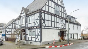 En traditionel bindingsværksbygning med et stejlt saddeltag, tydelig indgang og en lille veranda.