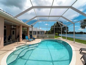 A covered outdoor swimming pool with lounge chairs and a patio area.