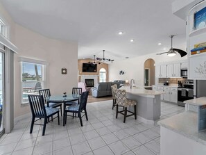A spacious kitchen with a dining area, a fireplace, and a large island. - Port Charlotte Lake front home Heated Pool, Dock (Port Charlotte)