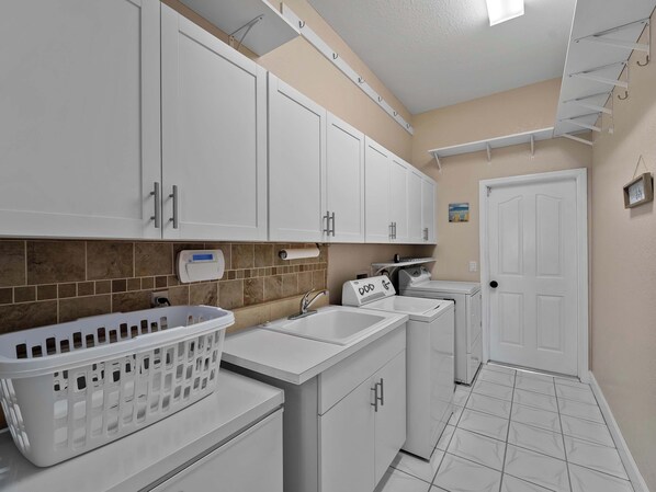 A compact laundry room with white cabinets, a washing machine, and a dryer.