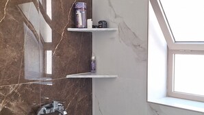 Une salle de bain moderne avec une douche, des murs en marbre et une lucarne.