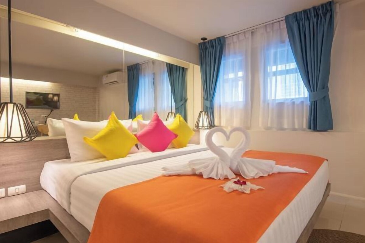 Une chambre d’hôtel avec un lit, des oreillers, une décoration en forme de cœur faite avec une serviette et un miroir.