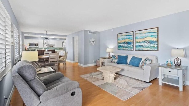 A modern living room with a grey sofa, a coffee table, and artwork on the wall. - Ilios Rentals (Fort Lauderdale)