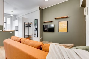 A modern living room with a sofa, a TV, and a framed menu on the wall.