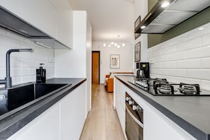 A modern kitchen with a black countertop, stainless steel appliances, and a wooden floor.