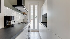 Una cocina moderna con armarios blancos, encimera negra, cafetera y estufa.