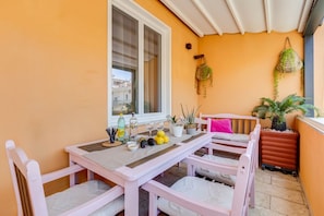 A balcony with a table and chairs, potted plants, and a hanging plant.