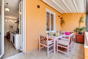 A dining area with a table and chairs, a window, and a kitchen in the background.